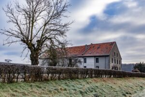 house-surrounded-by-greenery-with-hills-cloudy-sky-background_181624-9940